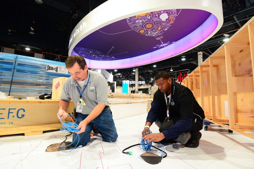 Cox technicians Eric Wieber (left) and Tracy Johnson pull CAT 5 Ethernet through plastic sheeting in the floor blueprint. 