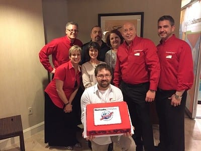 The Nomadic team celebrates their 40th anniversary with cake: Back row: Doug Turpin, Jim Casper, Gwen Parsons 2nd row: Stacy Barnes, Pat Goeke, Dave Evensen, Mike Rill Front row: Eric Hedge 