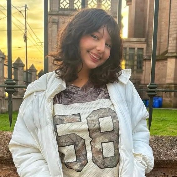 Elena Vazzo smiling outdoors while wearing a white jacket and patterned top.