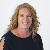 LeAnn Fischer smiling in a studio headshot, wearing a dark top with shoulder detailing.