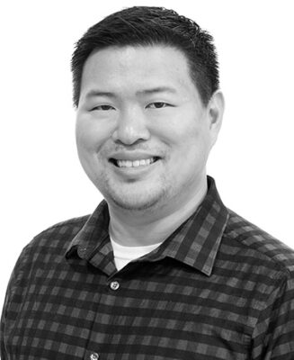 Man in a checkered shirt smiling in a studio portrait