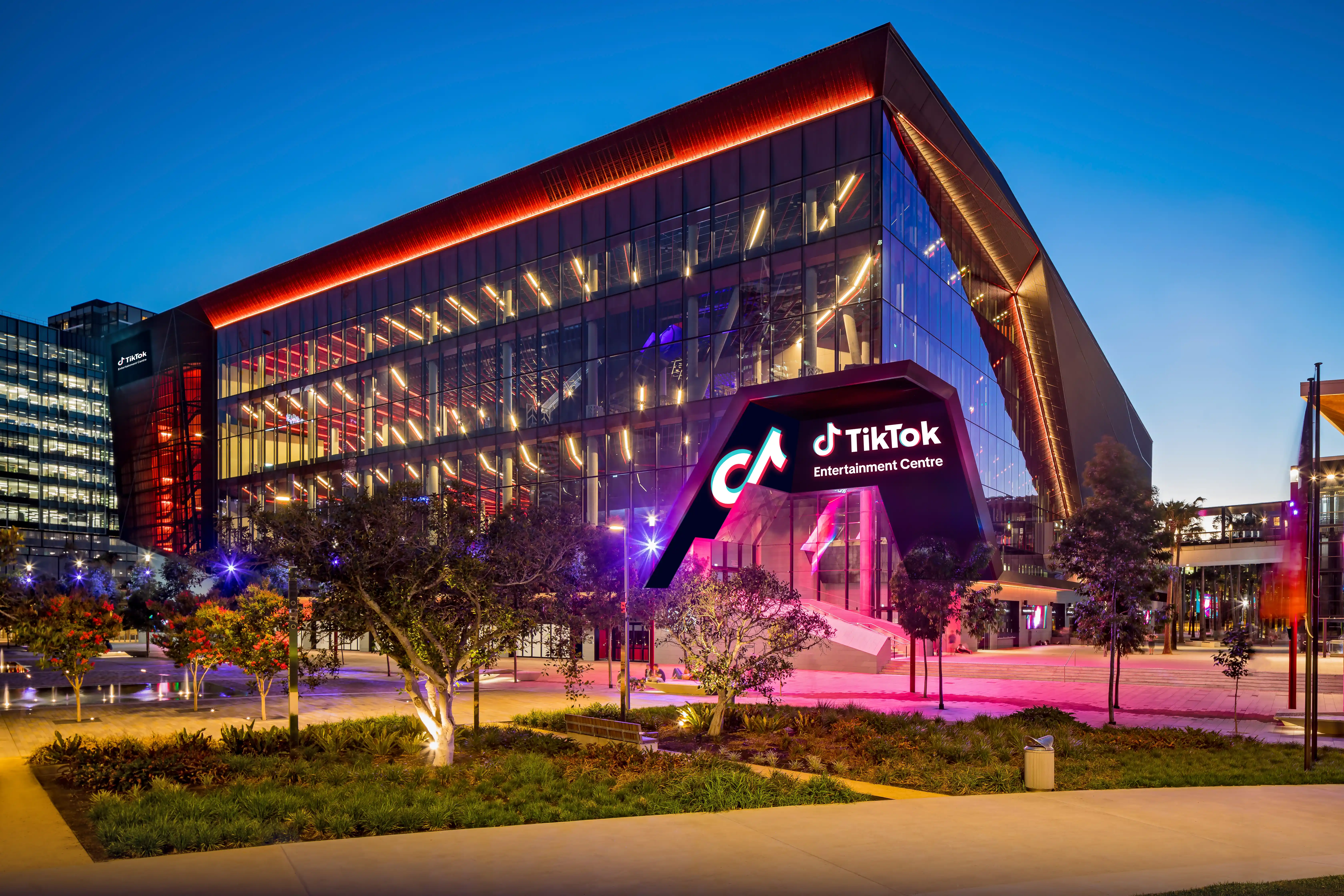 TikTok Entertainment Centre exterior at dusk, with illuminated signage and glass façade in Sydney.