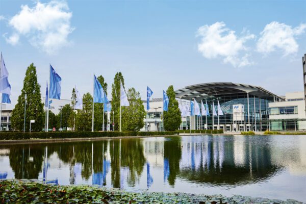 Messe München exhibition center in Munich, Germany, with flags and reflecting pool outside main entrance