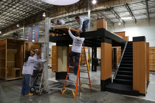 Tradeshow workers assemble a two-level exhibit during convention training.