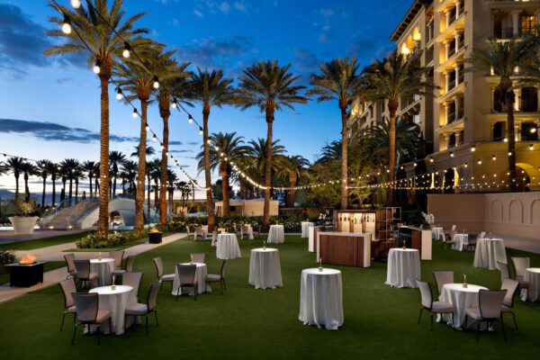 Outdoor event lawn at Green Valley Ranch Resort with palm trees, string lights, and cocktail tables.