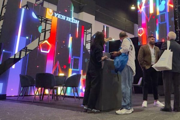 Attendees visit an exhibitor booth with colorful audiovisual displays at InfoComm América Latina.