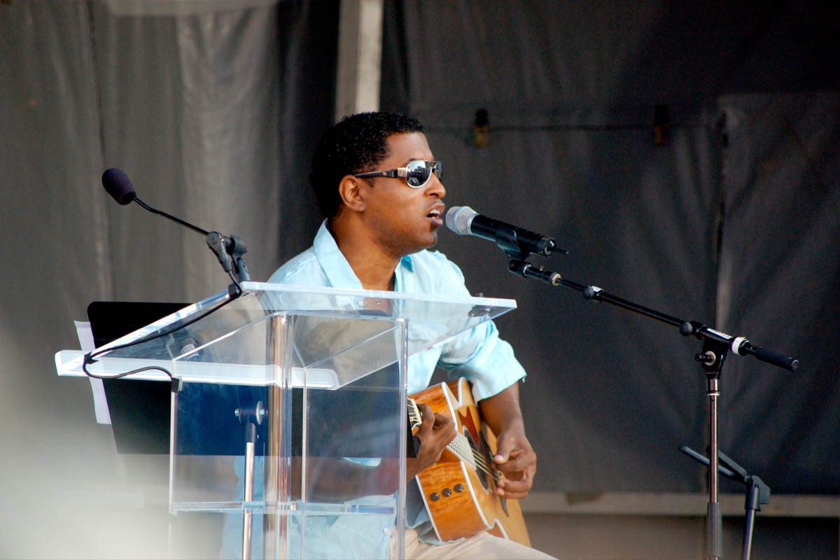 Babyface performs onstage with a guitar at a live event.