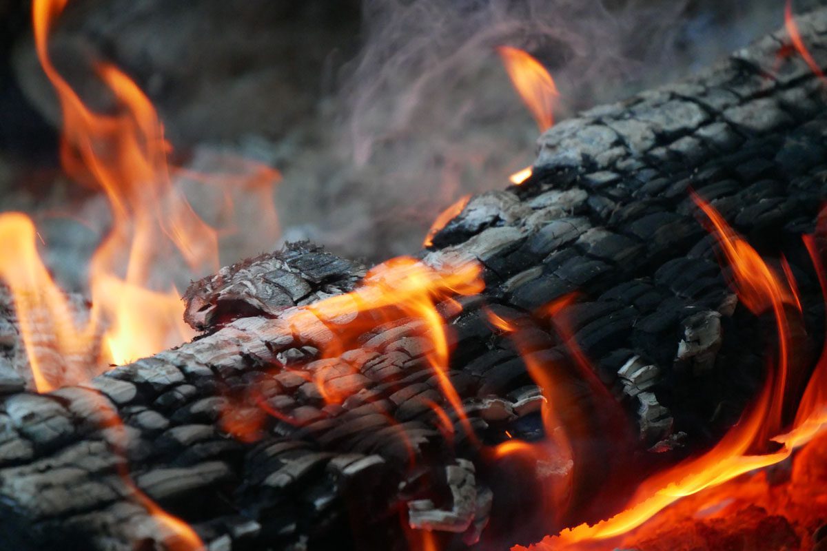 Smoldering logs with flames representing workplace burnout.