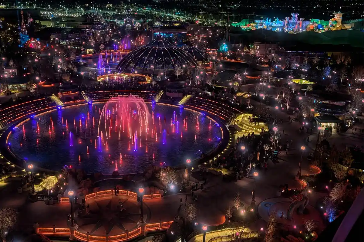 Nighttime aerial view of the illuminated Cosmos Fountain show and surrounding lands at Universal Epic Universe as seen from Universal Helios Grand Hotel in Orlando.