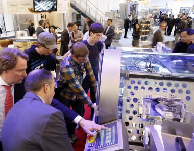 Attendees at Interpack2011 gather for a demonstration of a packing machine.